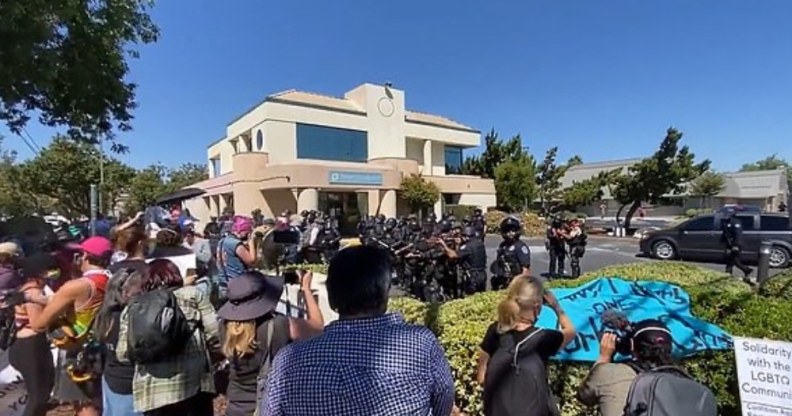 In this video screenshot, police circle protesters outside a building