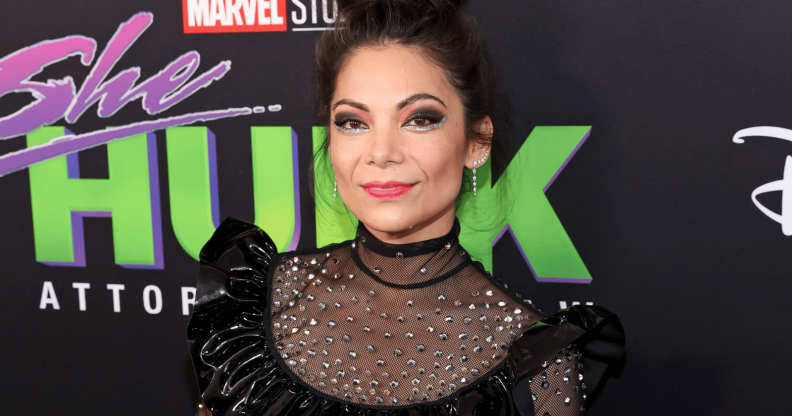 Ginger Gonzaga stands at the red carpet infront of a backdrop consisting of She-Hulk advertisements.