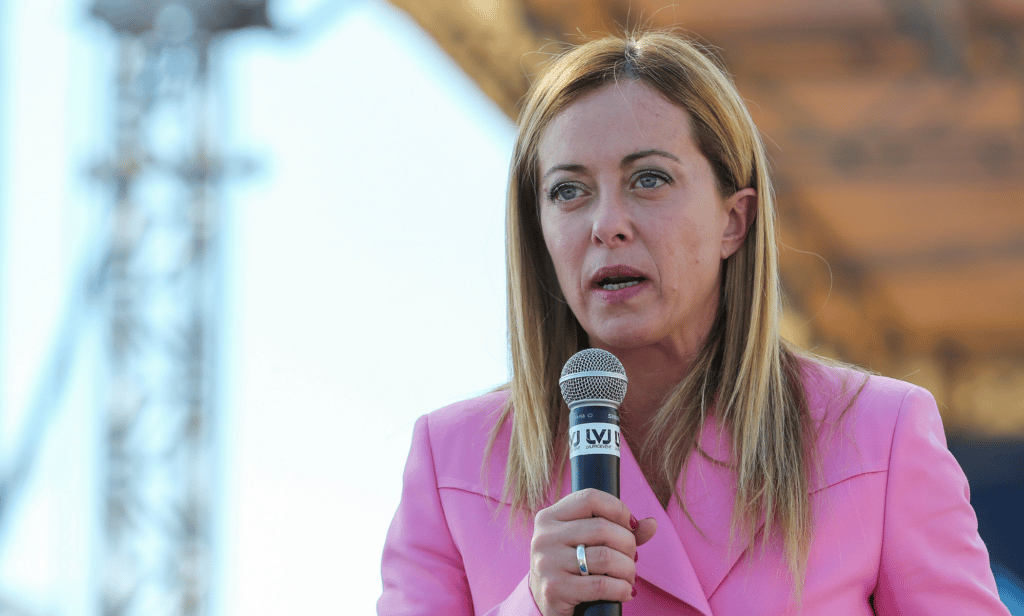 Giorgia Meloni wears a pink outfit as she speaks into a microphone