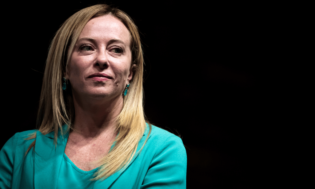 Giorgia Meloni wears a blue outfit as she stares at something off camera