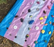 A flag laid out with stones at a vigil for the young trans man attacked during Pride celebrations