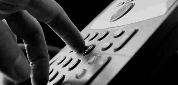 Close up of the fingers of a man dialing out on a land line telephone pressing the number keys on the keypad in a communications concept.