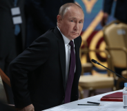 Vladimir Putin taking a seat during a political address