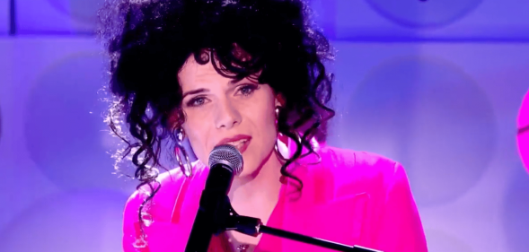 Jordan Gray wears a pink suit as she sings into a microphone during her Channel 4 Friday Night live performance