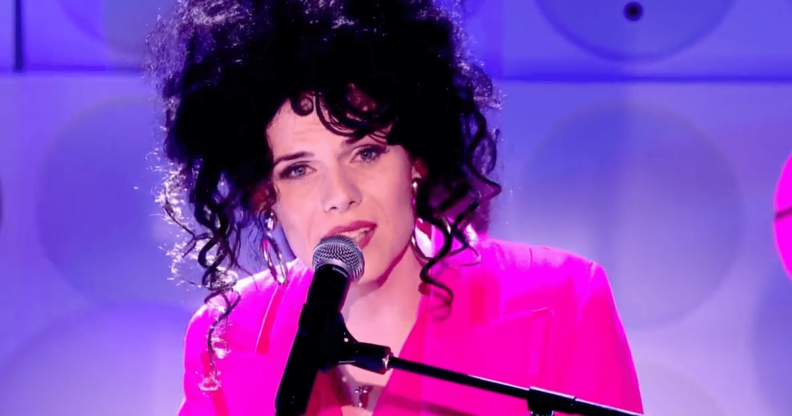 Jordan Gray wears a pink suit as she sings into a microphone during her Channel 4 Friday Night live performance