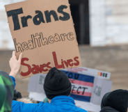 A person holds up a sign reading 'trans healthcare saves lives'