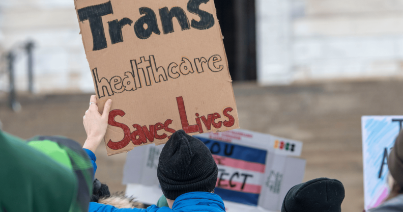 A person holds up a sign reading 'trans healthcare saves lives'