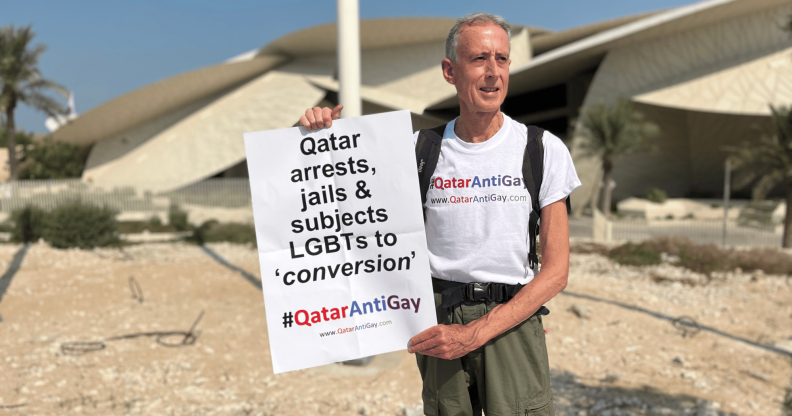 A photo of Peter Tatchell in Qatar holding his LGBTQ+ placard during his protest