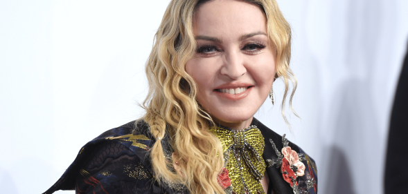 Madonna wears a sparkly green tie necklace with an embroidered outfit