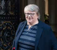 Thérèse Coffey wears a striped top as she walks out a door