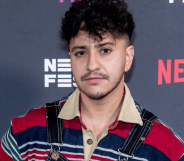 Zach Barack wears a striped shirt as he stands in front of a background with the Netflix logo on it