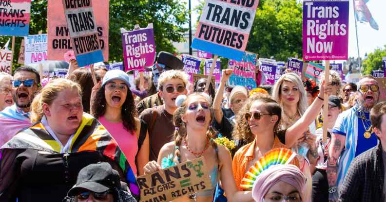 A large group of people holding pro-trans signs march through London during a Trans+ Pride march