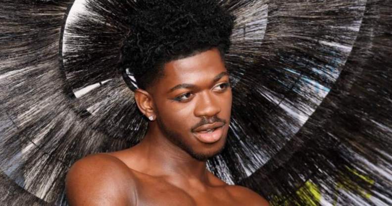 Lil Nas X wears a feathered headpiece as he poses for a photo