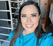 A Twitter screenshot of TV anchor Ashley Michels wearing a light blue top and smiling as she takes a selfie in the green room of KWGN news set.