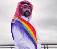 Dr Nas Mohamed wears Qatari attire with a sash in the colours of the LGBTQ+ Pride flag