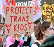 A photo shows a group of trans activists protesting, one sign being held says "Protect Trans Kids".