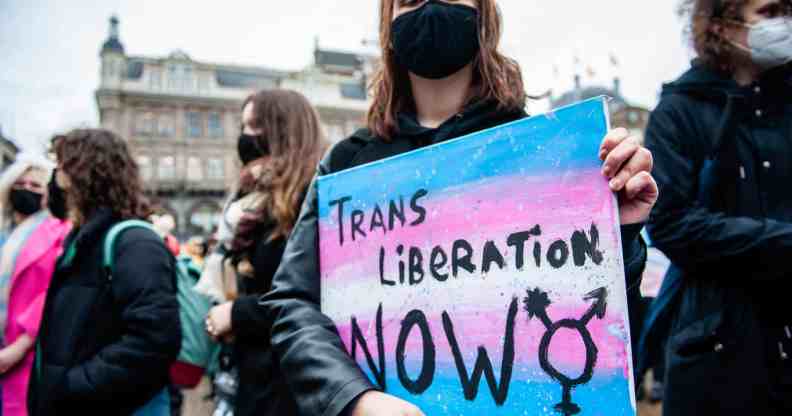 A trans protester holds a placard saying trans liberation now during a demonstration