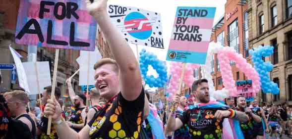 Picture showing people holding pro-trans placards as they march at a trans Pride parade in Manchester