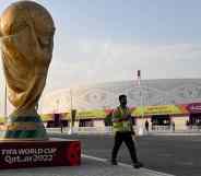 A stadium worker walks past a large statue of the World Cup in Qatar