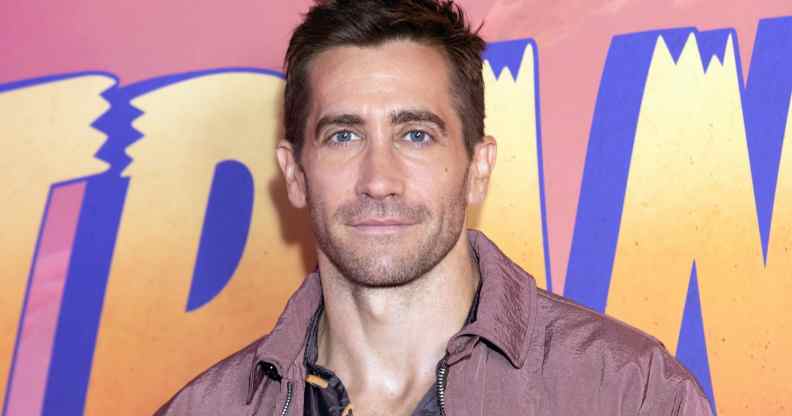 Jake Gyllenhaal infront of a logo of the Disney film Strange World