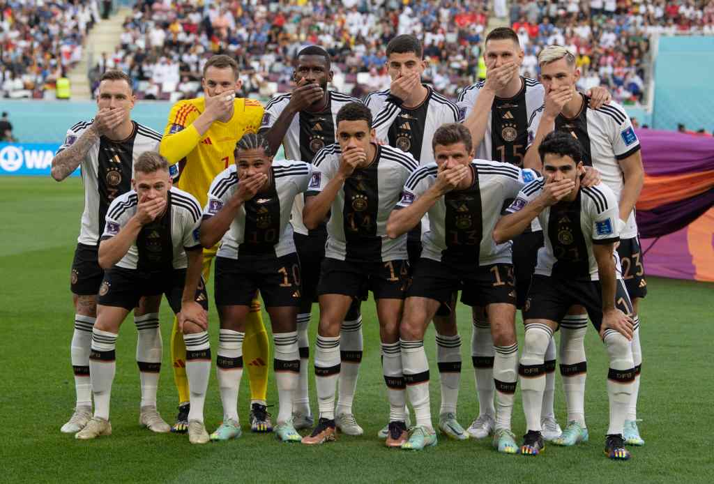 German football team members pose with their hands covering their mouths as they line up for the team photo ahead of the FIFA World Cup Qatar match between Germany and Japan