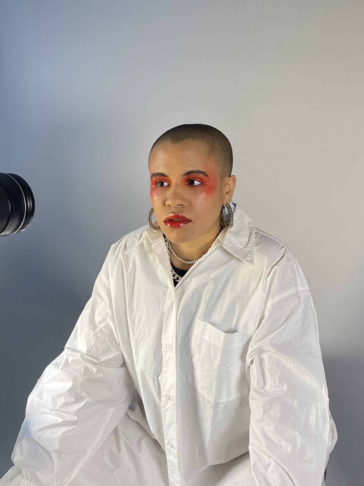 Ki Griffin taking part in a photoshoot wearing make-up and an all-white suit. 