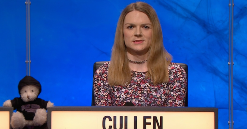 Emily Cullen appears on university challenge against a blue background, next to the team's teddy bear mascot