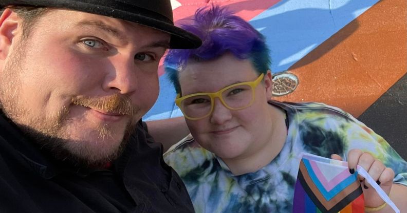 A photo of chef Dave Heide dressed in black and wearing a black hat with his arm round his child Ollie who's wearing a tie-dye t-shirt, yellow glasses and is holding a Pride flag