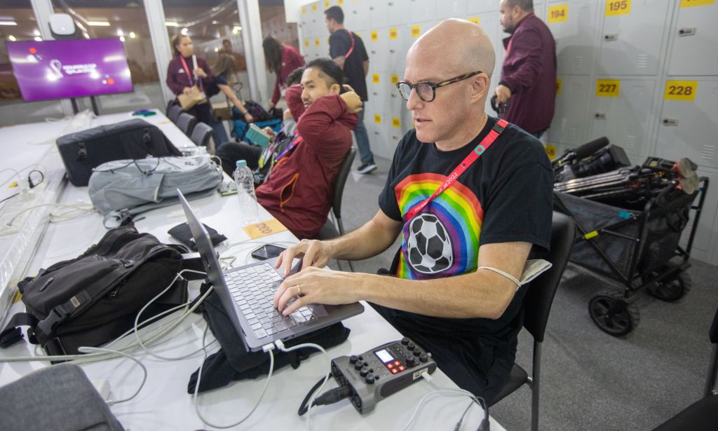 Sports journalist Grant Wahl typing on a laptop in the spacious media center of the Qatar World Cup.