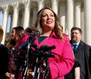 Lorie Smith, in a pink jacket, speaks outside the Supreme Court, with an array of microphones in front of her.