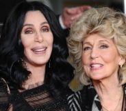 Cher, wearing a black dress, holds her mother, who is wearing a grey striped suit.