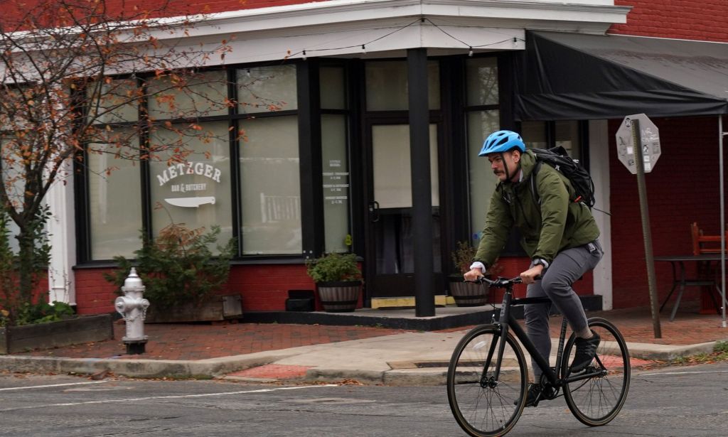 A cyclist in a blue helmet rides past the Metzger bar and butchery, which featured a print of their logo on the glass window.
