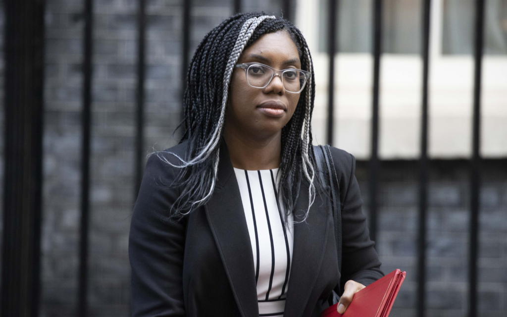 Kemi Badenoch walking past the door to Number 10 Downing street, holding a red folder.