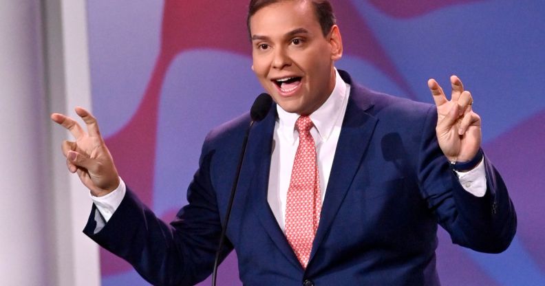 Republican politician George Santos gestures with his hands near his face while speaking at a podium