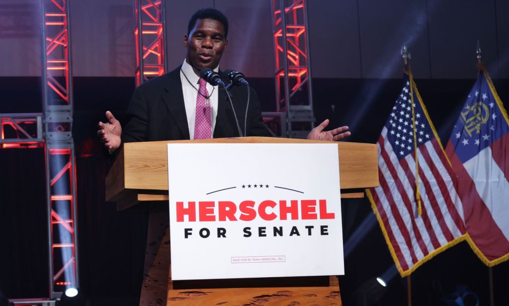 Herschel Walker stands at a podium with a sign with his name on it after he lost the Georgia Senate run-off election