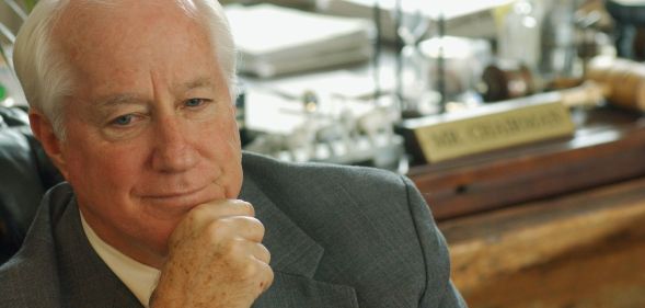 Jim Kolbe poses with his hand in front of his face as he sits down near a desk