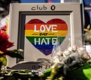 Flowers and a picture of a heart drawn in Pride rainbow colours with the message "Love over Hate" are placed outside Club Q