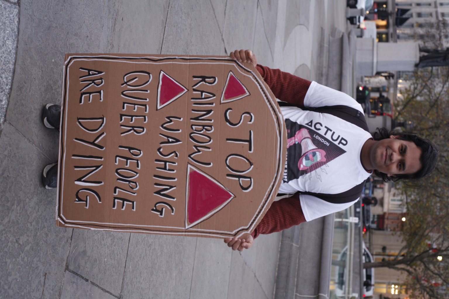 An activist holds a sign which reads: "Stop rainbow washing, queer people are dying"