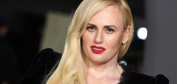 Rebel Wilson slightly tilted wearing red lipstick and a black dress, cropped to show her shoulder and head (Getty)