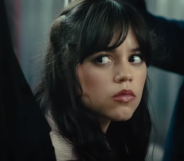 A still from upcoming movie Scream 6 shows actor Jenny Ortega with long dark hair sitting down in a subway train looking worried