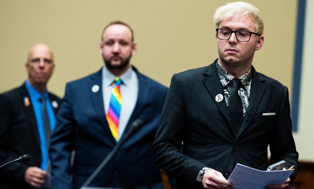 All three witnesses stand behind one another, with Michael Anderson wearing a black tie, James Slaugh wearing a rainbow tie, and Matthew haynes wearing a grey tie.