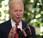 Joe Biden speaking into a microphone, there are Christmas trees in the background