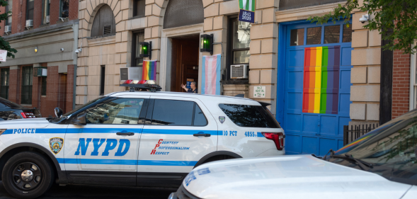 NYPD car in front of bar with rainbow flag