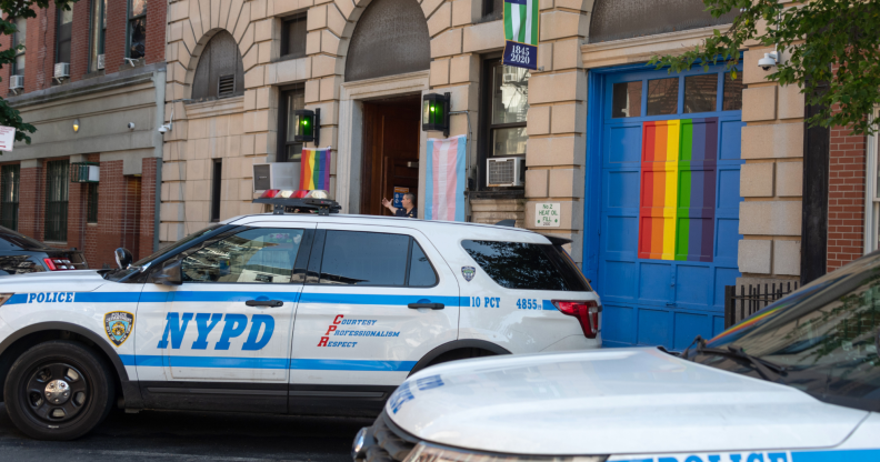 NYPD car in front of bar with rainbow flag