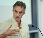 Jordan Peterson speaks during a lecture while wearing a slightly yellow t shirt