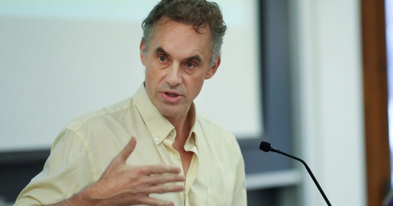 Jordan Peterson speaks during a lecture while wearing a slightly yellow t shirt