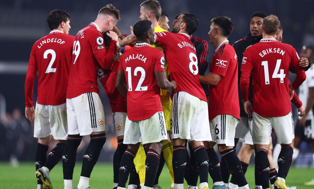 Manchester United players, wearing red football uniforms, gather around each other