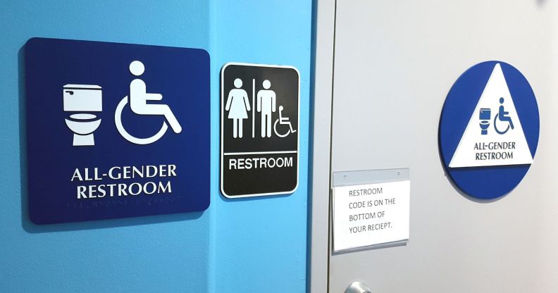 Signs on a wall show members of the public that the bathroom is an 'all gender restroom' and inclusive of trans people