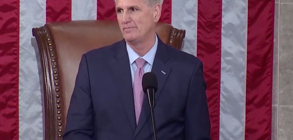 Republican congressman Kevin McCarthy, who is wearing a suit and tie, stands at a podium in front of the red, white and blue US flag as he's sworn in as speaker of the House of Representatives