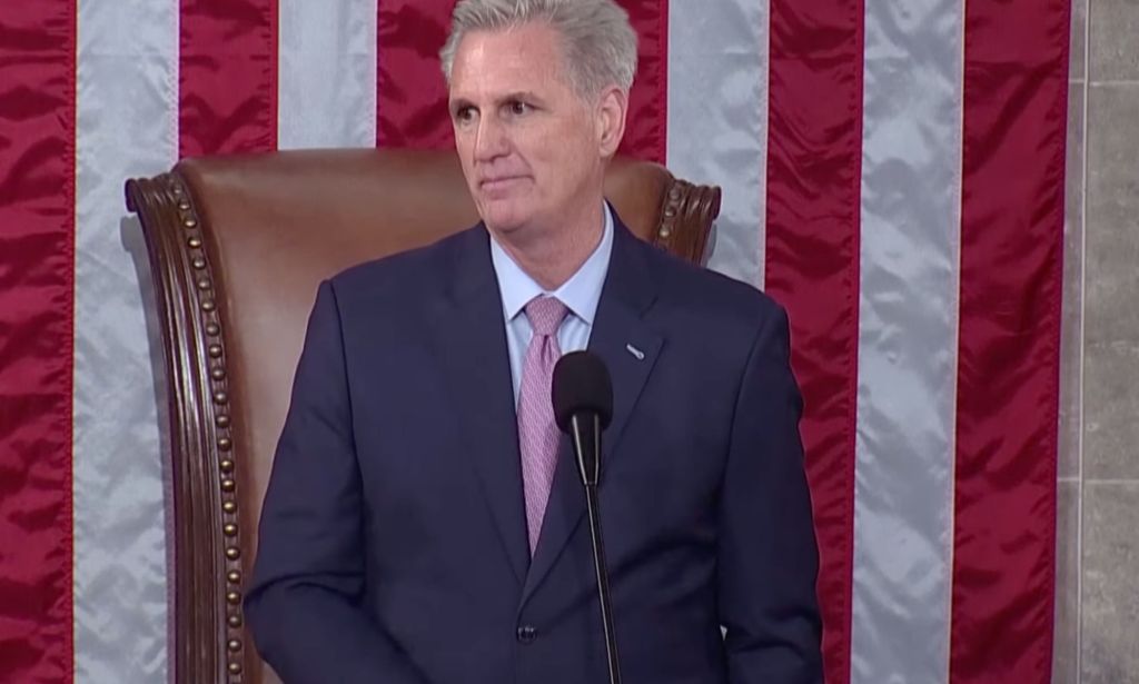 Republican congressman Kevin McCarthy, who is wearing a suit and tie, stands at a podium in front of the red, white and blue US flag as he's sworn in as speaker of the House of Representatives